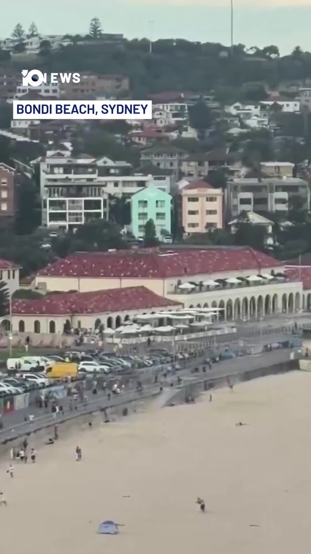 At least three people are dead in a shooting incident at Bondi Beach. Footage posted to social media shows crowds at Bondi running as multiple gunshots ring out. Additional footage appears to show two gunmen firing from a bridge overlooking the beach. NSW Police are urging people at the scene to remain in shelter